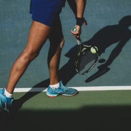 woman holding tennis ball and racket