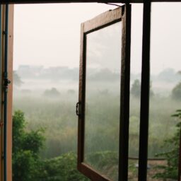 an open window with a view of a foggy field