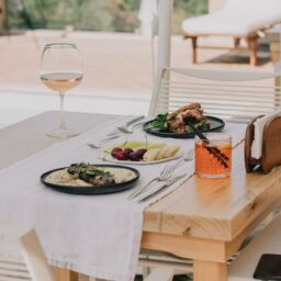 An elegant outdoor dining table with a gourmet meal and drinks, perfect for a summer gathering.