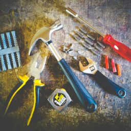 Collection of hand tools including hammer, screwdriver, and pliers in a workshop setting.